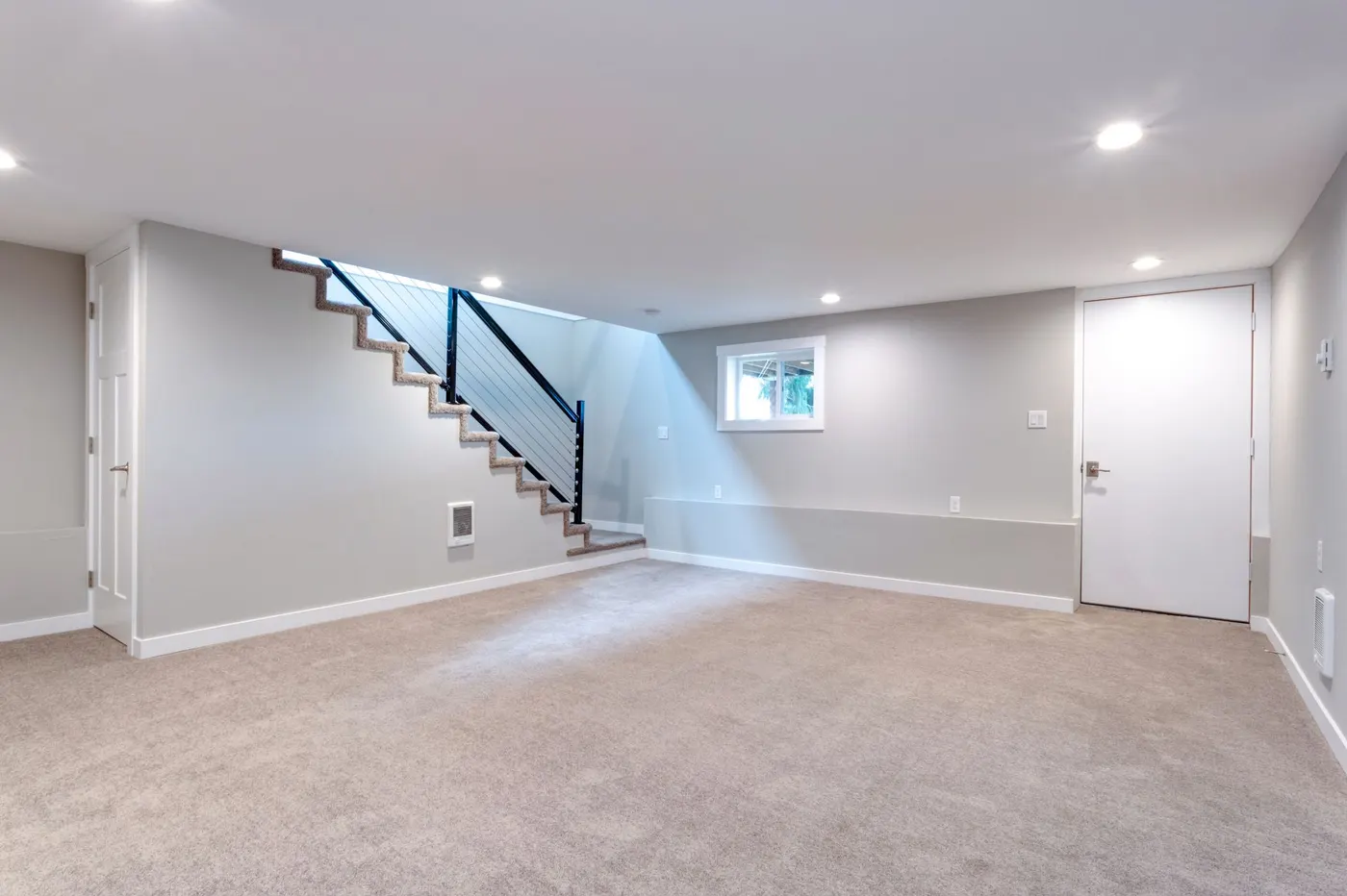 A finished basement with carpet, recessed lights and an open stair