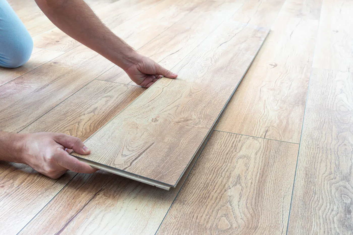A flooring installer locking a laminate plank into place