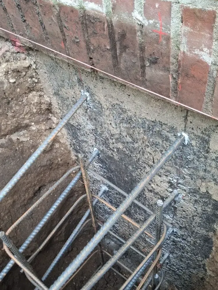 An excavated foundation wall with its black waterproof coating