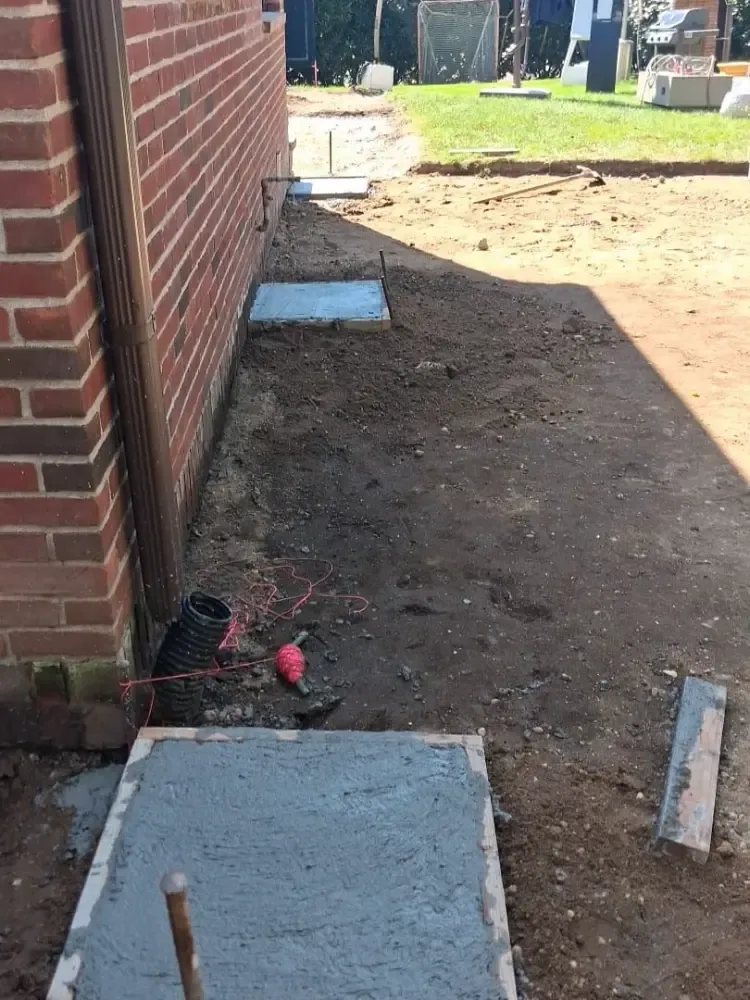 A drain pipe and new footings along a brick foundation