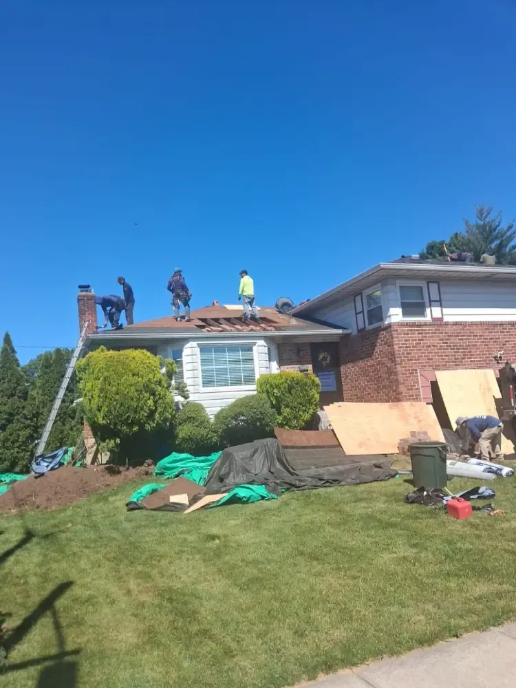 Our crew stripping an old roof, with tarps protecting the yard